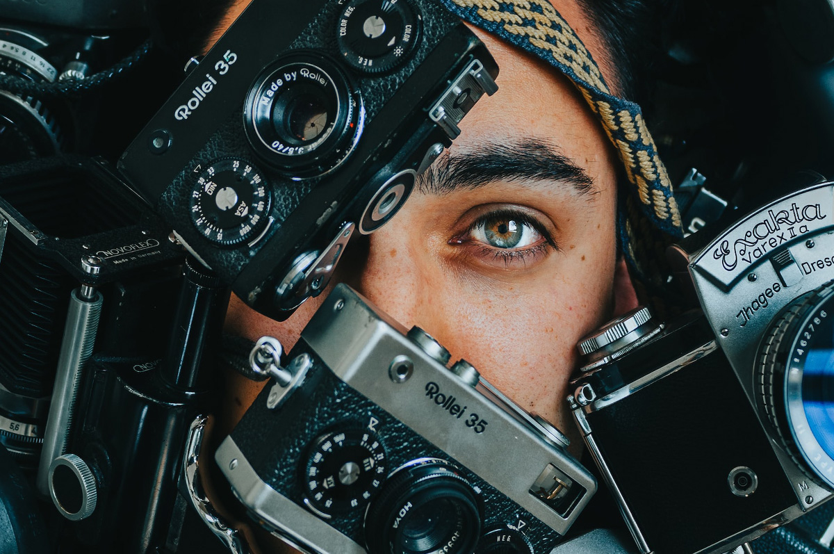 Photo of a woman with cameras around her.